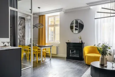 a living room with a dining room table and yellow chairs at District17 by StayLab in Kraków