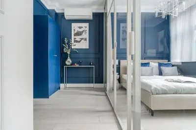 a bedroom with blue walls and a bed and a mirror at District17 by StayLab in Kraków