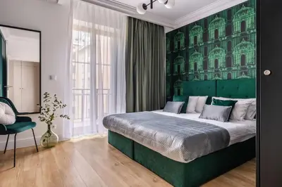 a bedroom with a large bed with a green headboard at District17 by StayLab in Kraków
