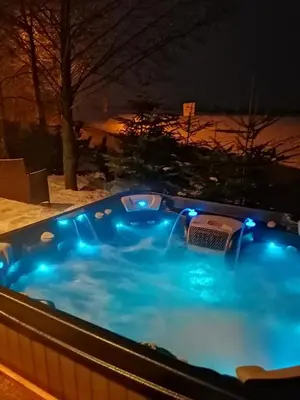 a hot tub with blue lights in a backyard at night at LendHouse - SPA pod Gwiazdami in Sąspów