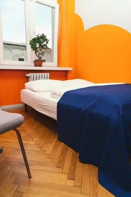 a bedroom with orange walls and a bed with a blue blanket at LazeMaze Hostel in Kraków