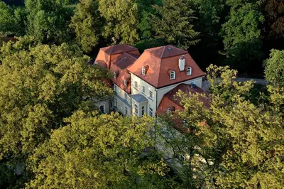 a large house with a red roof in the trees at Dwór Sieraków in Sieraków