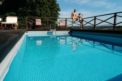 a man sitting on a fence next to a swimming pool at Dwór Sieraków in Sieraków