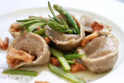 a white plate of food with mushrooms and asparagus at Dwór Sieraków in Sieraków