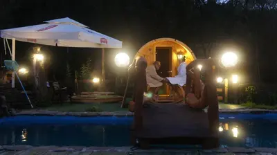a group of people sitting on a playground by a pool at night at Zajazd pod Chmurką in Rabka