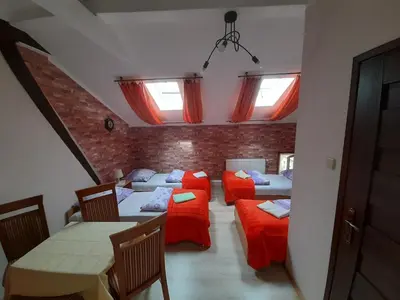 a room with four beds and a table and chairs at Green Hostel in Kraków