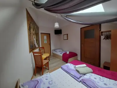 a small bedroom with two beds and a chair at Green Hostel in Kraków