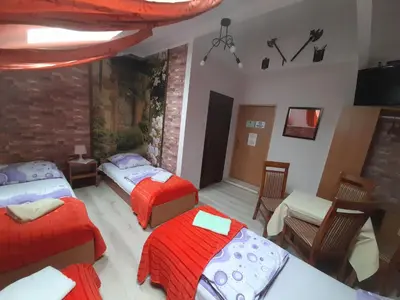 a room with two beds and a table and chairs at Green Hostel in Kraków