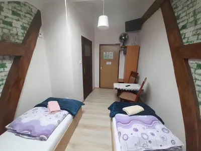 two beds in a small room with a table at Green Hostel in Kraków
