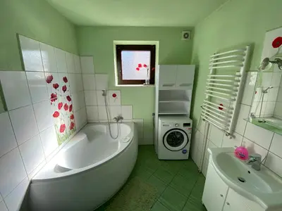 a bathroom with a tub and a sink and a washing machine at Dom do wynajęcia 