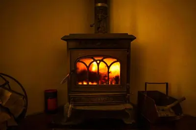 a woodburning stove with a fire in a room at KrakowHouse in Libertów