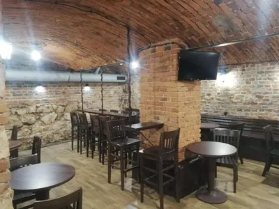 a bar with wooden tables and chairs in a brick wall at Lorf Hostel&Apartments in Kraków