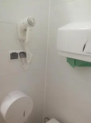 a bathroom with a toilet and a blow dryer at Lorf Hostel&Apartments in Kraków