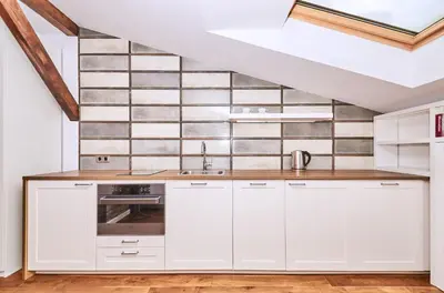 a kitchen with white cabinets and a tile wall at Chodkiewicza 10 (A) - cozy studio by Homeprime in Kraków