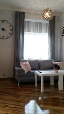 a living room with a couch and a table and a clock at Royals Flower Apartments III in Kraków