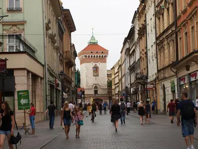 a group of people walking down a street with buildings at Royals Flower Apartments III in Kraków