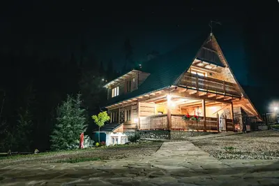 a large wooden house with a gambrel roof at night at Góralska Willa in Nowy Targ