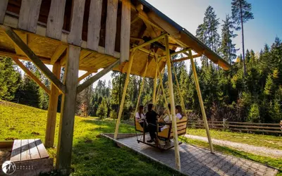 a group of people sitting on a porch swing at Góralska Willa in Nowy Targ