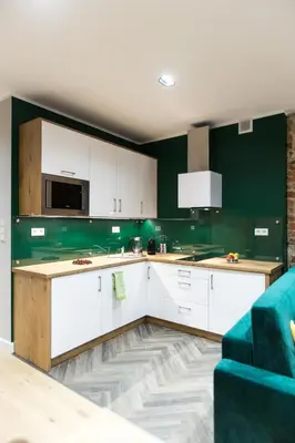 a kitchen with white cabinets and green walls at Luxury in the Heart of the Old Town in Kraków