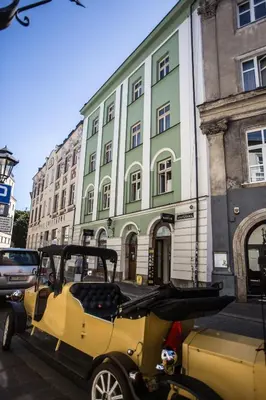 a yellow golf cart parked in front of a building at Luxury in the Heart of the Old Town in Kraków