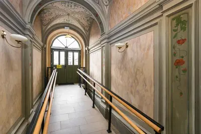 a hallway with a staircase in a building with flowers on the walls at City of the Kings Arianska Garden in Kraków
