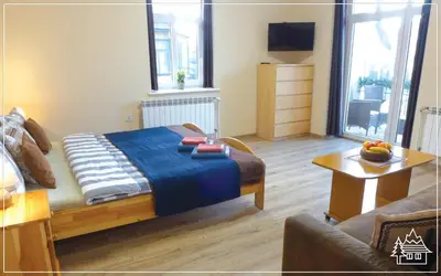 a bedroom with a bed and a couch and a table at Przystanek Rabka - Apartamenty w centrum in Rabka