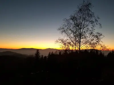 a sunset in the mountains with a tree in the foreground at Mountain cabin in Pcim