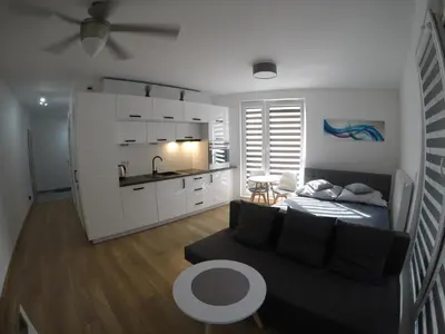a living room with a couch and a kitchen at Apartments Olit Bajeczna in Kraków