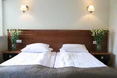 two beds in a bedroom with two vases with flowers at Villa Julia in Kraków