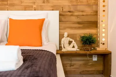 a bed with an orange pillow sitting on a wooden table at Cracow Best Location Apartment with Garden by Cozyplace in Kraków