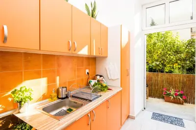 an orange kitchen with a sink and a window at Cracow Best Location Apartment with Garden by Cozyplace in Kraków