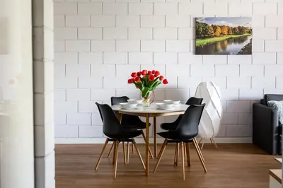 a dining room with a table and chairs with a vase of flowers at River Side Residence nr 1m7 in Oświęcim