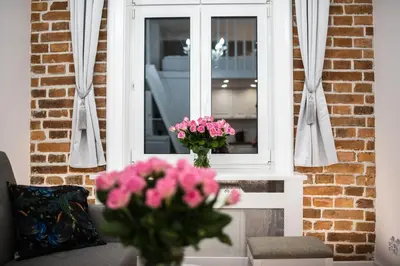 a vase of pink flowers sitting in front of a window at Saint Philip in Kraków