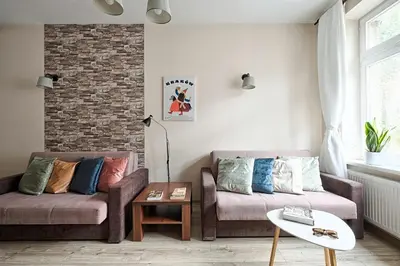 a living room with two couches and a brick wall at Urban Nest Apartments Józefitów 5 in Kraków