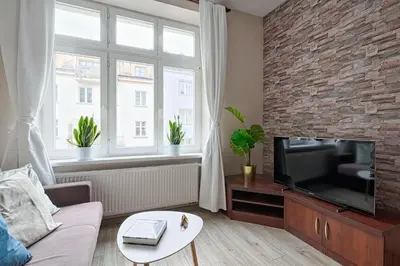a living room with a tv and a brick wall at Urban Nest Apartments Józefitów 5 in Kraków