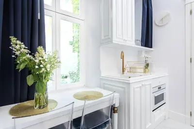a white kitchen with a vase of flowers on a counter at Golden Fish - New Apartment - Old Town in Kraków