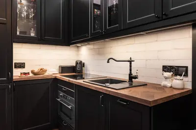 a kitchen with black cabinets and a sink at Wooden Horse - New Apartment - Old Town in Kraków