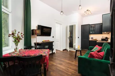 a living room with a table and a green couch at Wooden Horse - New Apartment - Old Town in Kraków