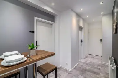 a kitchen with white walls and a wooden counter with plates on it at Rainbow Apartments 1 Premium in Kraków