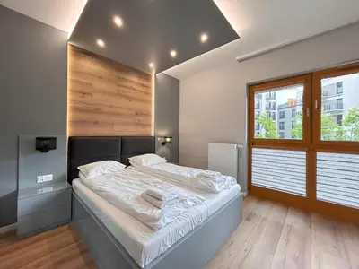 a white bedroom with a bed and a sink at ApartmentPrestige Central Station in Kraków
