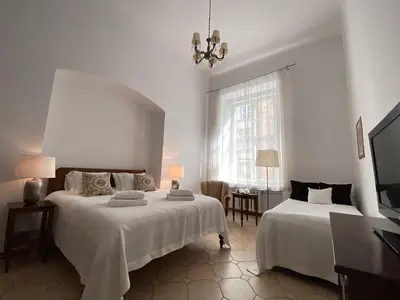 a white bedroom with two beds and a window at Boutique Aparthotel in Kraków