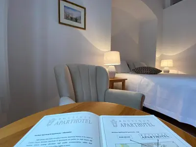 a room with a bed and a table with a book at Boutique Aparthotel in Kraków