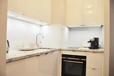 a kitchen with white cabinets and a sink at Rakowicka 22H - studio by Homeprime in Kraków