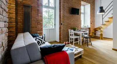 a living room with a couch and a brick wall at Miodowe mieszkanko in Kraków