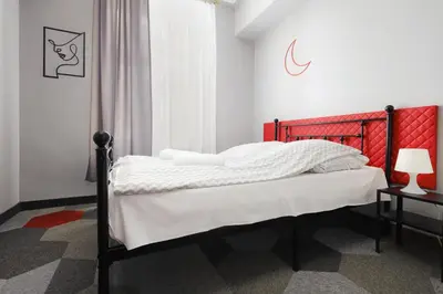 a bedroom with a bed with a red headboard at Moon Hostel Kraków in Kraków