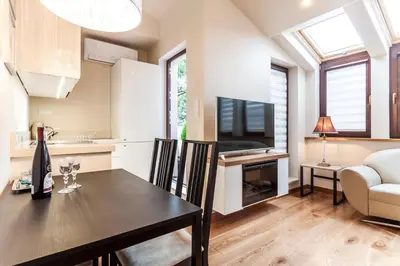 a kitchen and living room with a table and a television at Parkside Apartments Old Town in Kraków