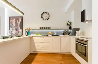 a kitchen with white cabinets and a clock on the wall at Old Town Premium Kazimierz Apartments in Kraków