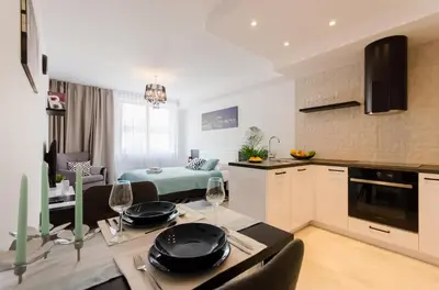 a kitchen and a living room with a table and chairs at Old Town Premium Kazimierz Apartments in Kraków