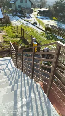 a fence with snow on the grass and a house at Gdow Riverside Apartments and Tours in Gdów