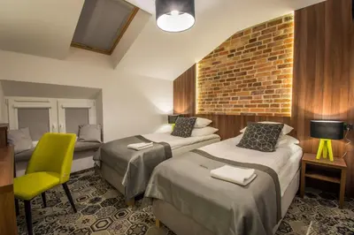 a hotel room with two beds and a yellow chair at Hotel Lavender in Kraków